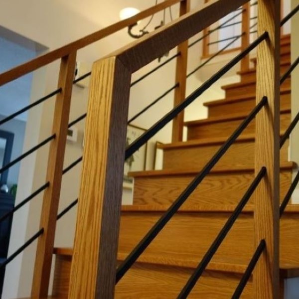 continous handrail with horizontal black metal balusters and red oak stair tread recap