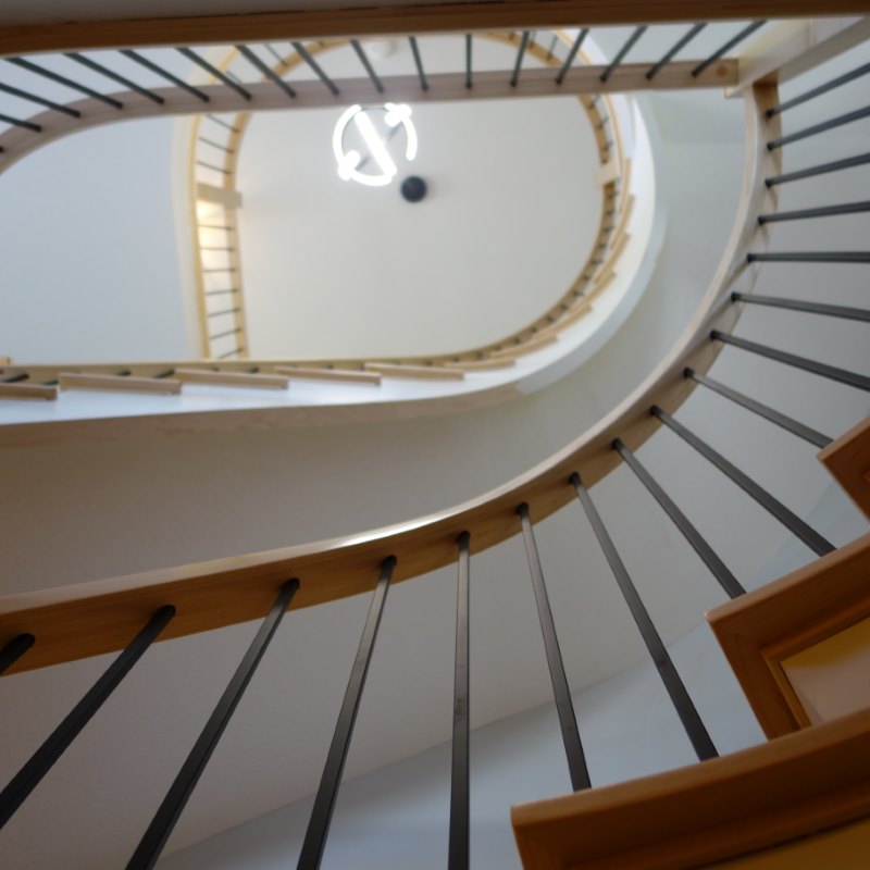 curved railing system maple hardwood with metal balusters, natural maple staircase with a custom radius on the winder treads