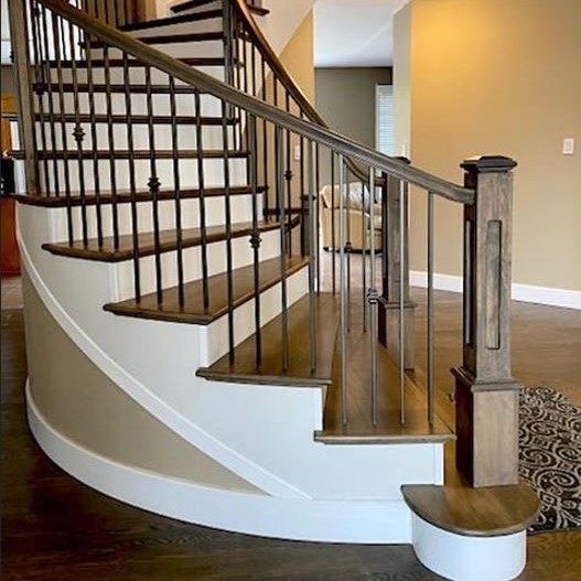 Curved staircase installation with wrought iron balusters